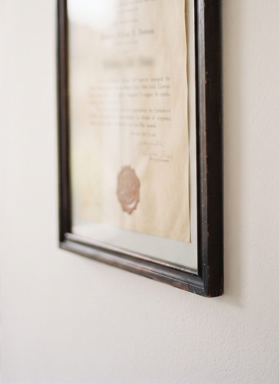 Gerahmte Urkunde an einer hellen Wand, schräg im Fensterlicht fotografiert.